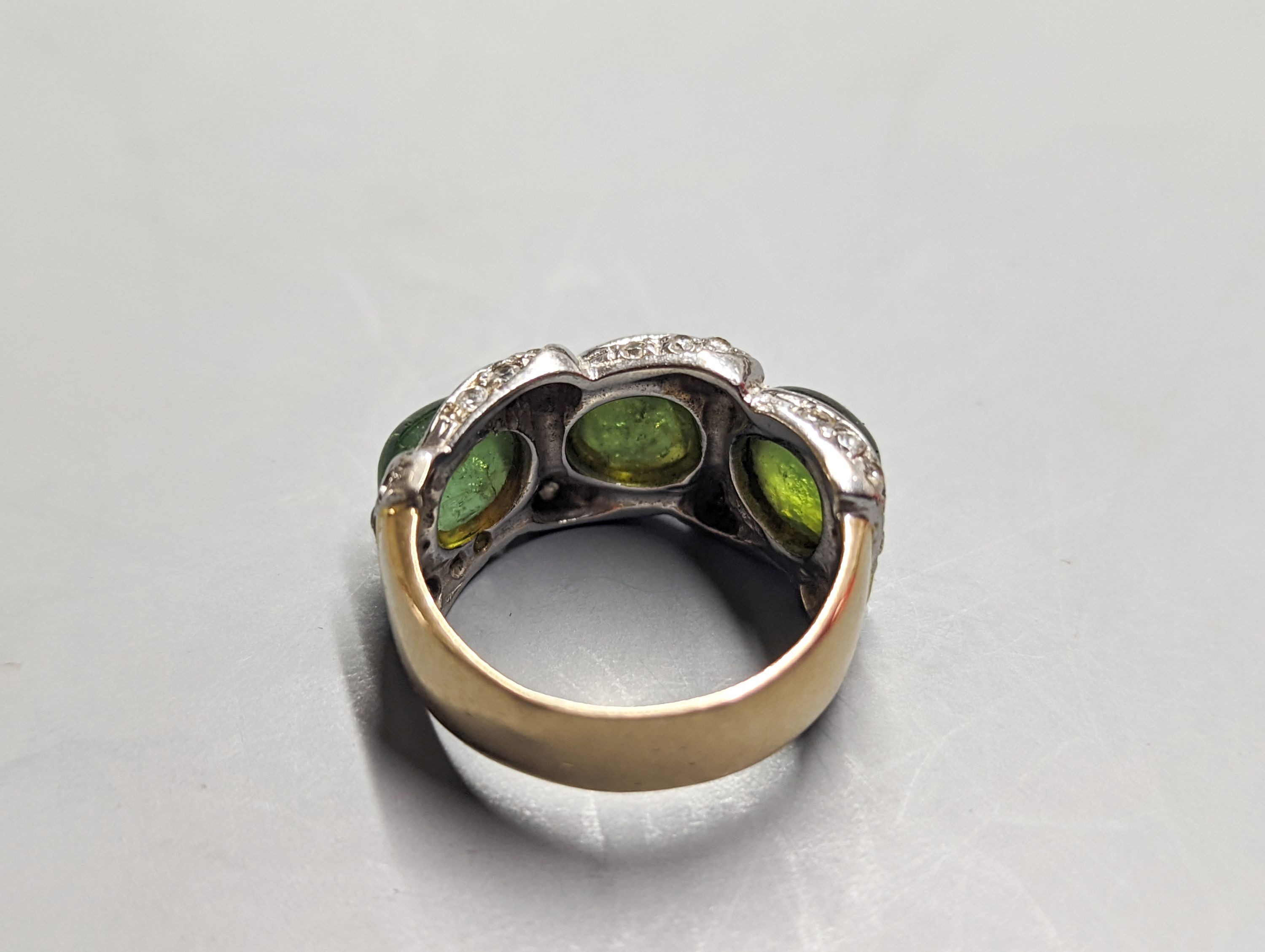 A modern 585 yellow metal, three stone green cabochon and diamond chip set dress ring, size N/O, gross weight 8.3 grams.